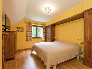 A bedroom with a bed, wooden wardrobe, a window with curtains, and a ceiling light fixture. - Tenneville Villa With Sauna (Tenneville)