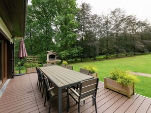 An outdoor deck with a dining table and chairs, a barbecue grill, and a wooden planter with plants. - Tenneville Villa With Sauna (Tenneville)