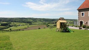 A rural landscape with a wooden playhouse and a brick building. - Holiday Home in Limbourg With Garden (Limbourg)