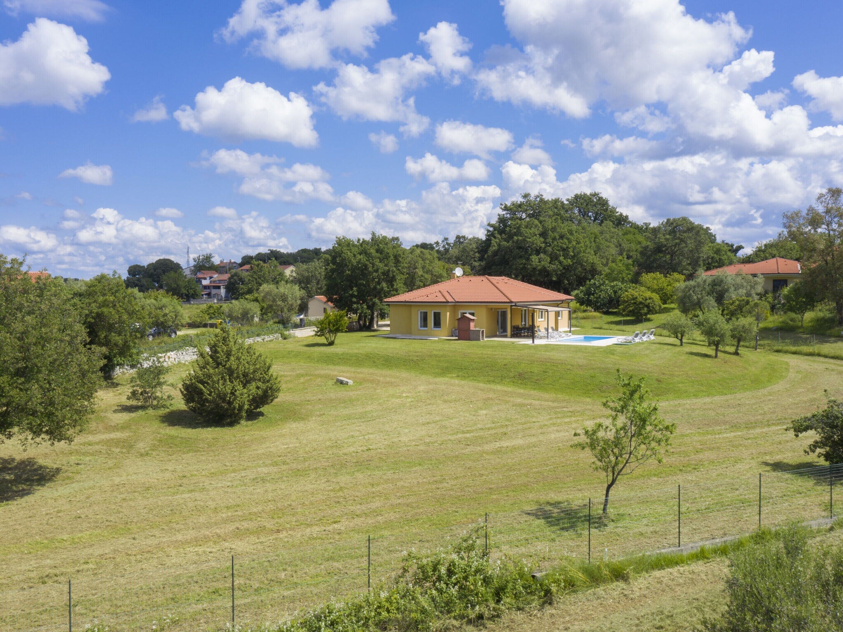 A house with a red roof, a swimming pool, and a fenced yard.