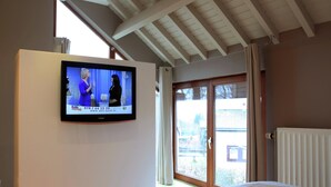 Ett sovrum med en säng, en tv som är monterad på väggen och en skjutdörr i glas som leder ut till ett utomhusområde.