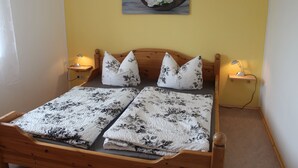 A bed with floral bedding, two bedside lamps, and a wall-mounted picture of flowers in a boat. - Chicke Ferienwohnung in Struppen (Struppen)