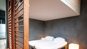 A modern bedroom with a bed, wooden floor, and a small bedside table with a light. - Holiday Home in Denee for 21 People (Anhée)