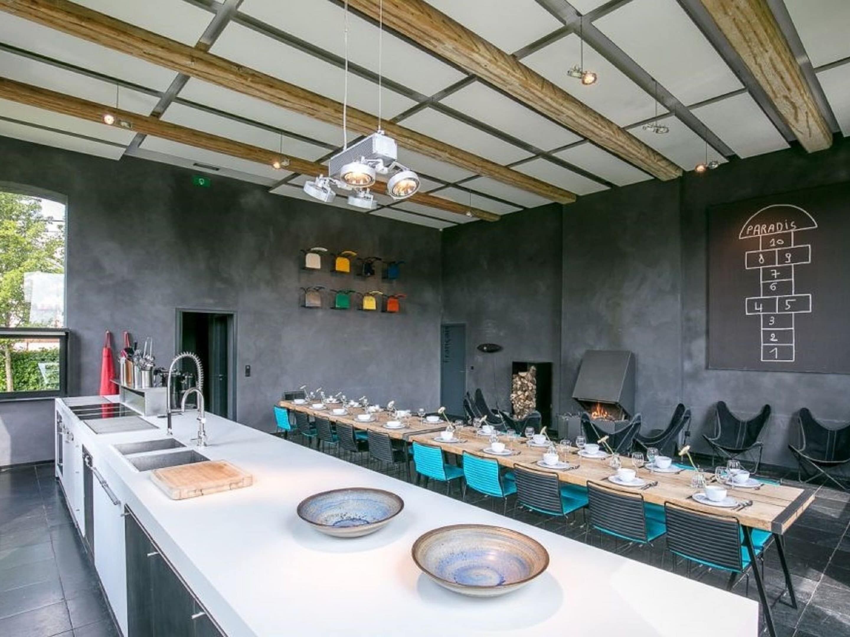 A modern kitchen with a long island, a fireplace, and a chalkboard menu.