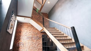 A modern staircase with a brick wall and a wooden handrail. - Holiday Home in Denee for 21 People (Anhée)