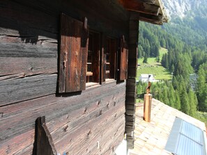 A wooden cabin with a balcony overlooking a mountainous landscape.