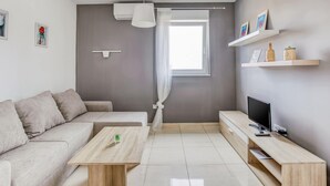 Een moderne woonkamer met een bank, salontafel, televisie en boekenkasten.