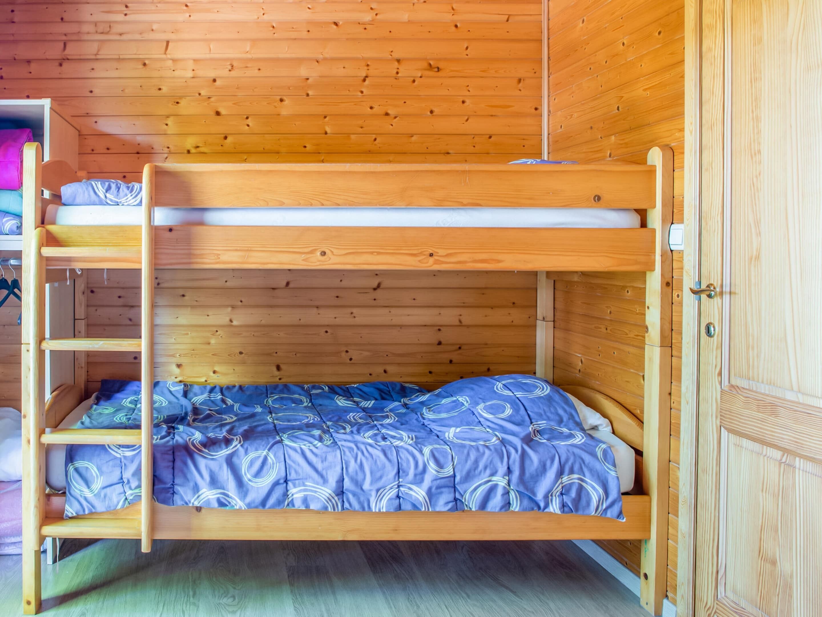 A bunk bed with a wooden frame and a blue patterned bedspread.
