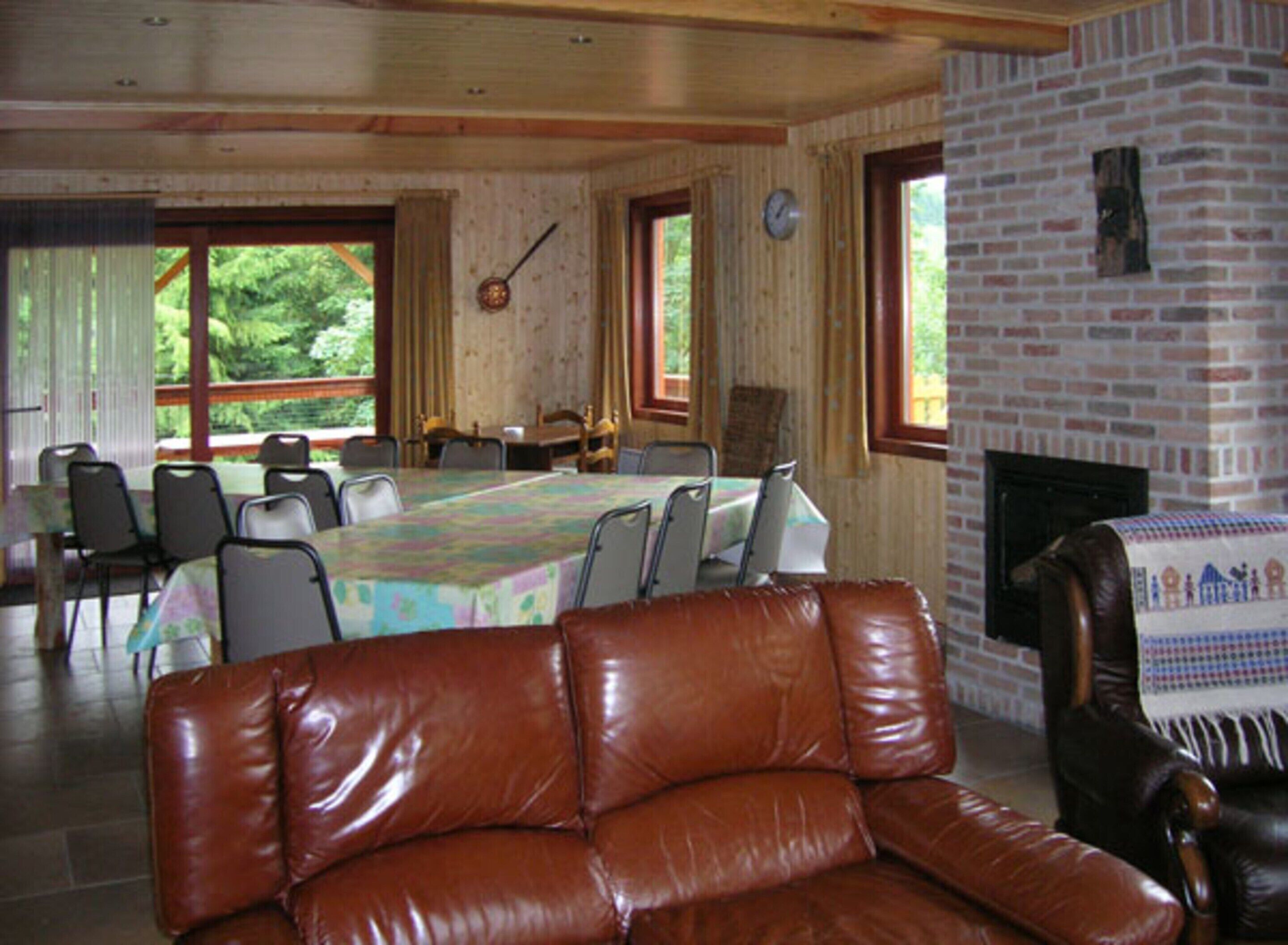 Una habitación con una mesa grande dispuesta para comer, sillas de cuero, una chimenea y un reloj en la pared.