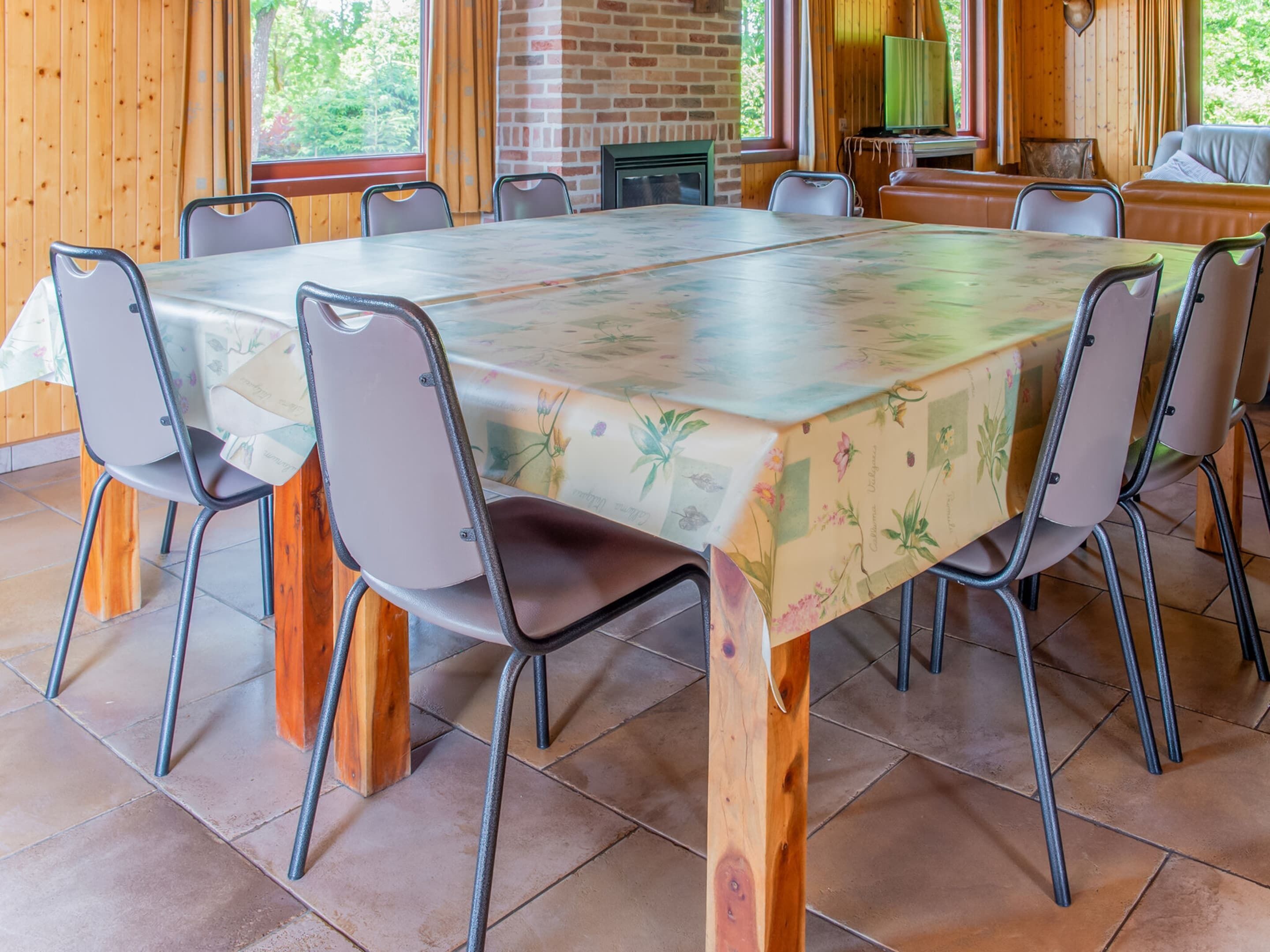 Een eetruimte met een lange tafel, stoelen en een bakstenen muur.