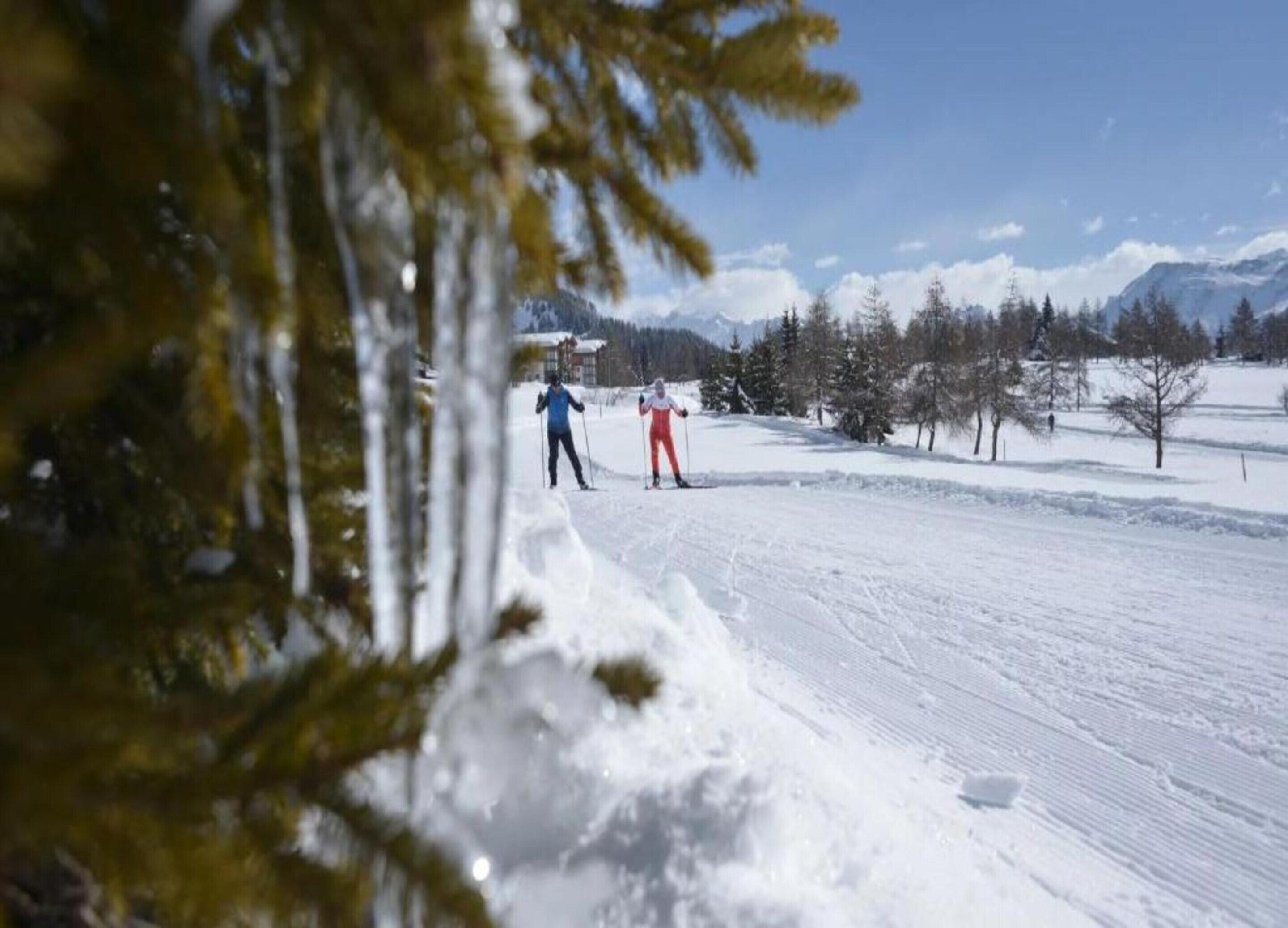 A snowy landscape with two skiers in the distance.