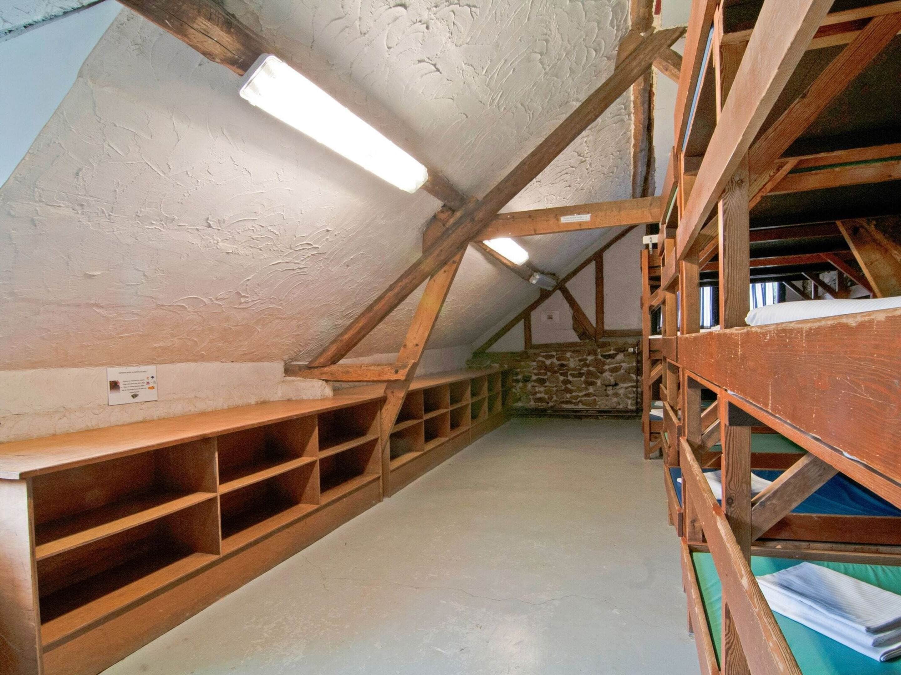 An attic room with wooden shelving, a stone wall, and a sloped ceiling.
