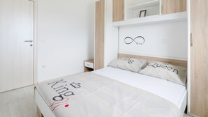 A bedroom with a bed, a wardrobe, and a shelf with decorative items. - Apartment in Novalja Near Zrce Beach (Novalja)