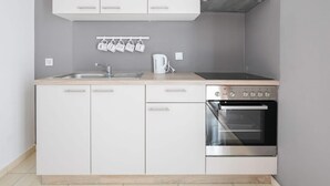 A compact kitchen with white cabinets, a stainless steel oven, and a coffee maker. - Apartment in Novalja Near Zrce Beach (Novalja)