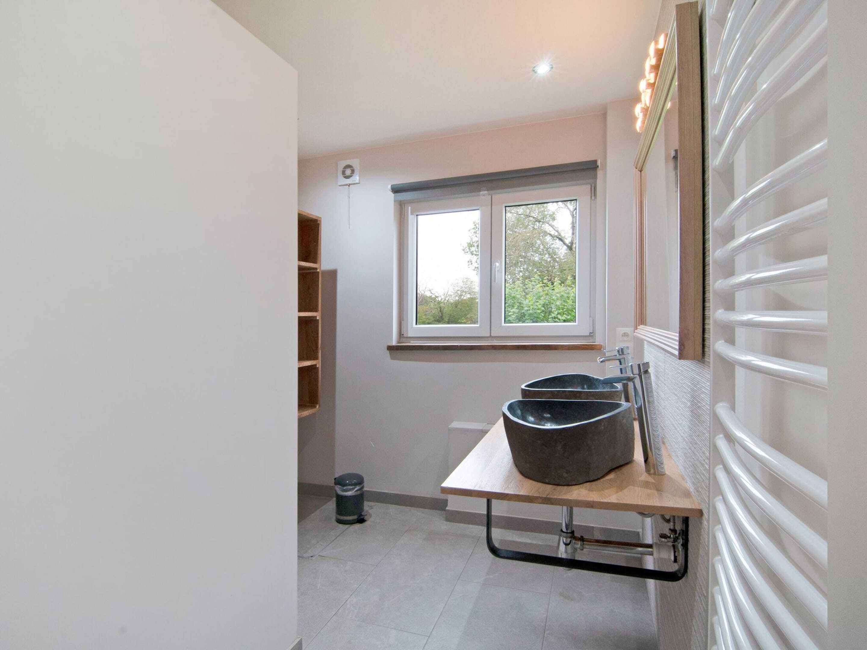 Ein modernes Badezimmer mit großem Fenster, einer Holzhilfe und einem integrierten Waschbecken.