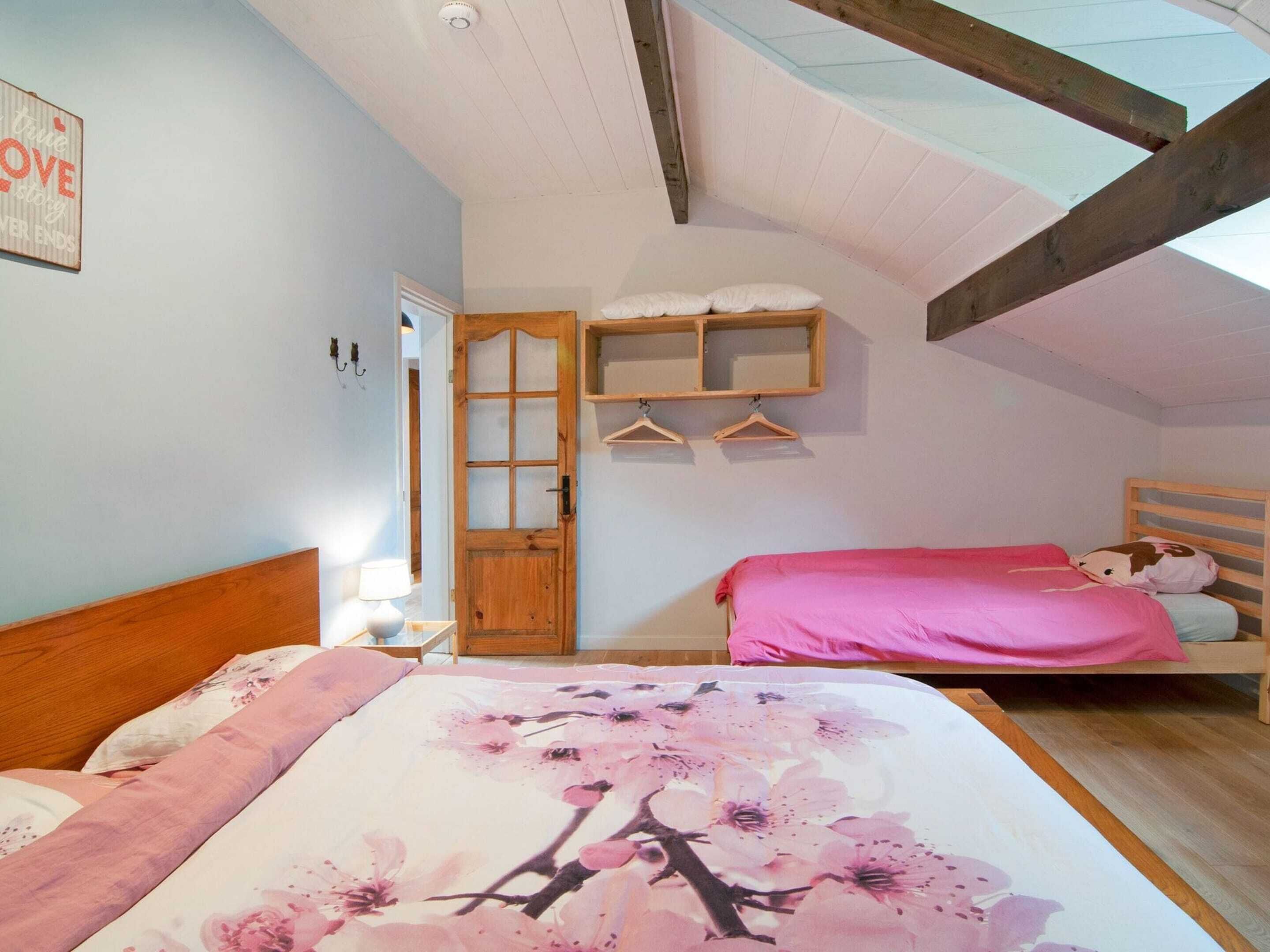 Camera da letto con due letti, testiere in legno, una porta in legno e una mensola a parete con attaccapanni.