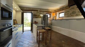 Een moderne keuken met een accentmuur van steen, een inbouwoven en een groot kookeiland met barkrukken.