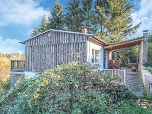A rustic cabin with a wooden exterior, a stone chimney, and a covered patio area. - Chalet in Guntersberge Near Ski Trails (Harzgerode)