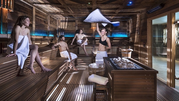 A sauna room with wooden benches, a stone basin, and a wooden sauna cabin. - Belvilla by Oyo Baita Morena Due Trilo (Livigno)