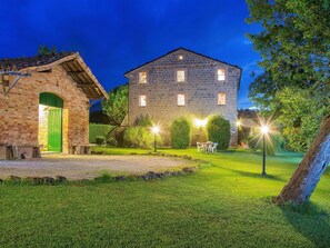 Un bâtiment en pierre avec une porte verte et un espace extérieur bien éclairé, aménagé pour accueillir des clients.