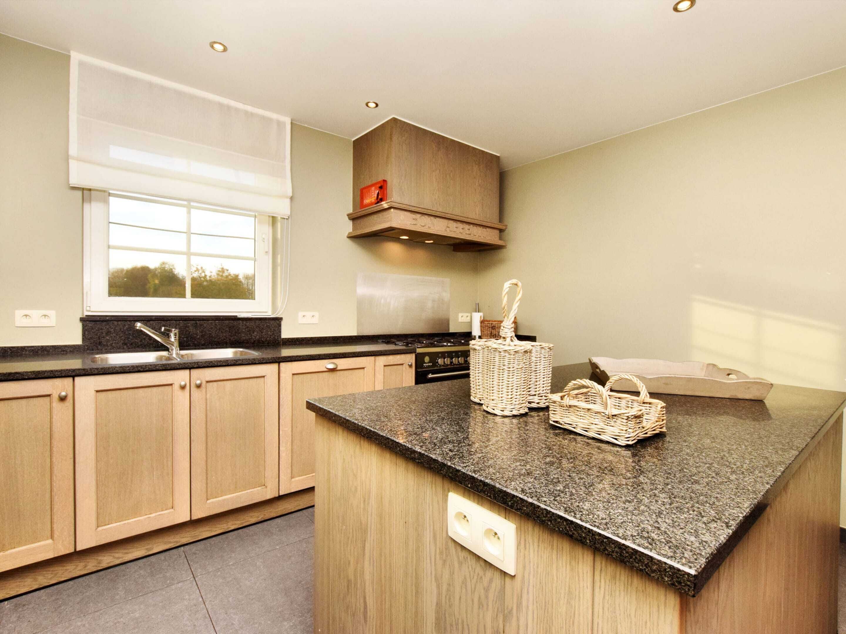 A modern kitchen with wooden cabinets, a granite countertop, a built-in stove, and a window with blinds.