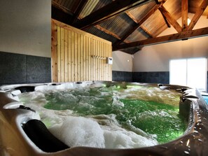 Un bain à remous avec de l’eau verdâtre, des murs en bois et un sol carrelé.