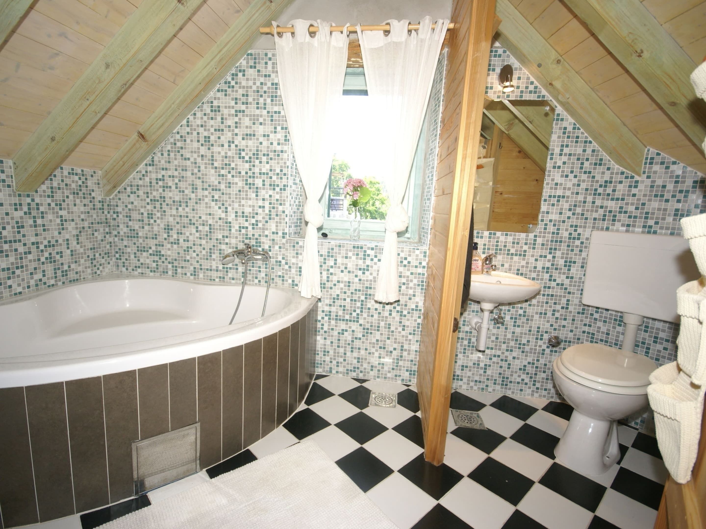A bathroom with a bathtub, a sink, and a toilet. The floor has a black and white checkered pattern.