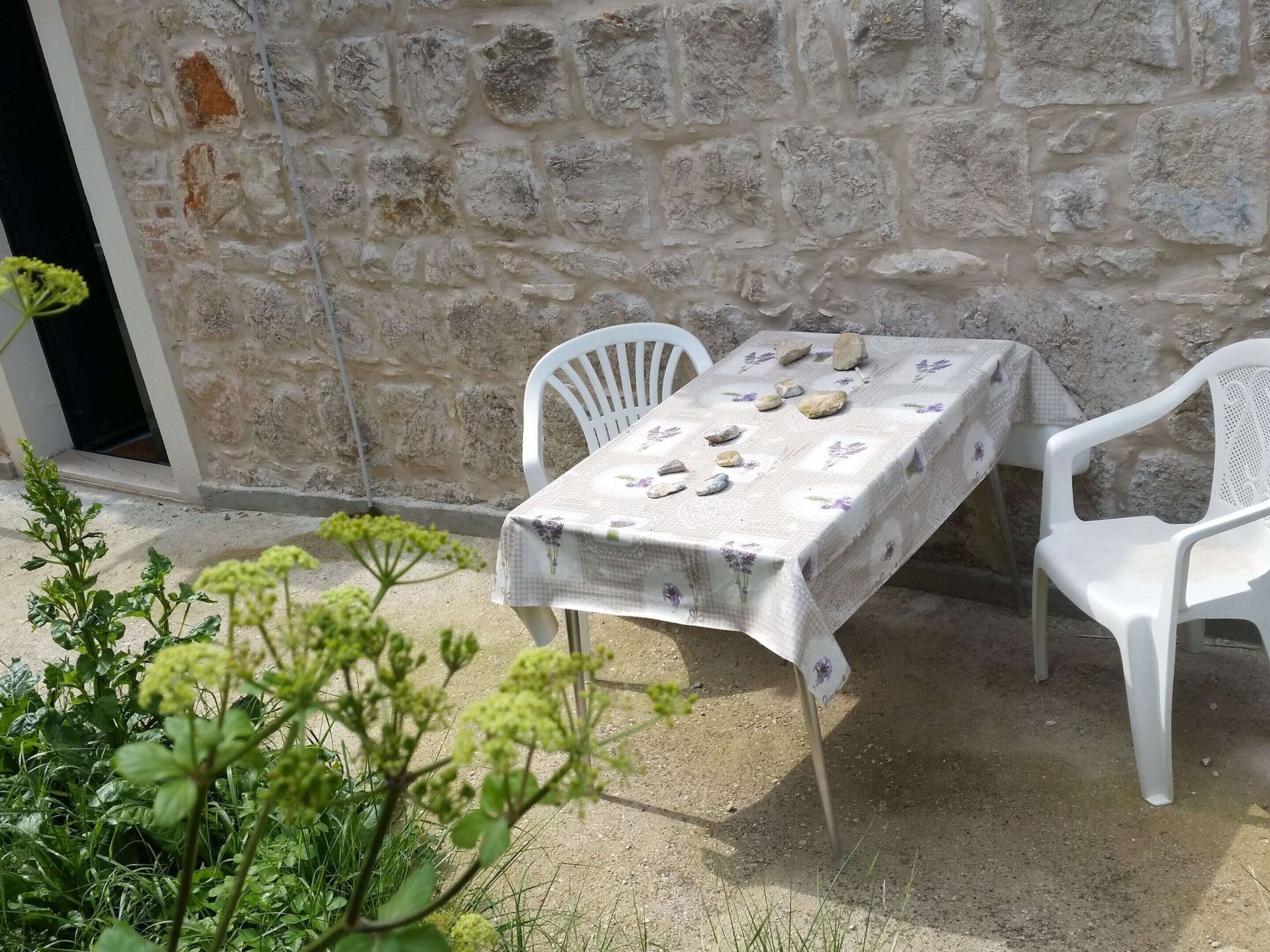 Eine Steinsäule mit einem Tisch und zwei weißen Plastikstühlen.