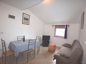 A small, well-lit room with a dining table and chairs, a sofa, a television, and a window with curtains. - Apartment in Banjole Near Temple of Augustus (Medulin)