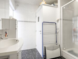 A bathroom with a white sink, a mirror, a toilet, a shower with a glass door, and a towel rack. - Simplistic Apartment in Blankenberghe near Belgium Pier (Blankenberge)