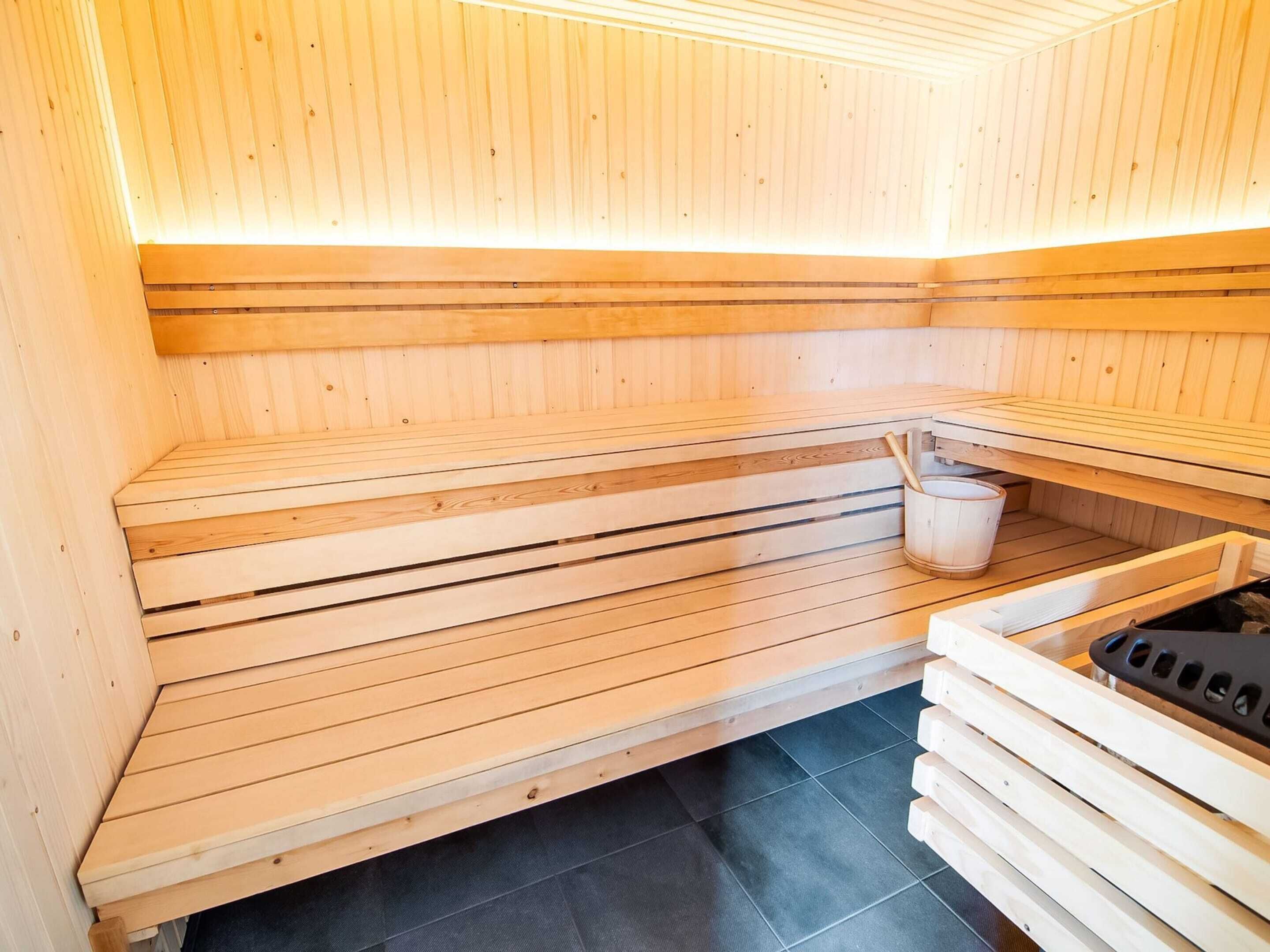 A sauna with wooden benches and a black heater.