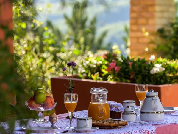 Una preparación para el desayuno con una mesa, frutas, bebidas y una jarras de jugo de naranja.