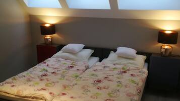 A bedroom with a skylight, two bedside tables with lamps, a bed with floral bedding, and a nightstand.