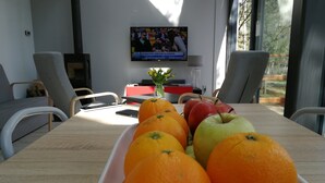 A dining table with fruits and a TV in the background. - Glass Cottage in Jelenska Huta With Terrace (Szemud)