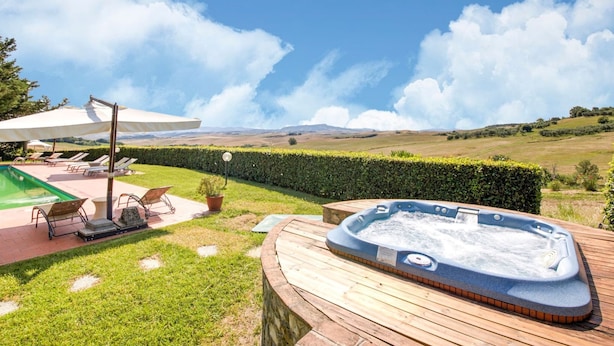 A hot tub on a wooden deck with a view of rolling hills and a clear sky. - Belvilla by OYO San Francesco Vermentino (Lajatico)