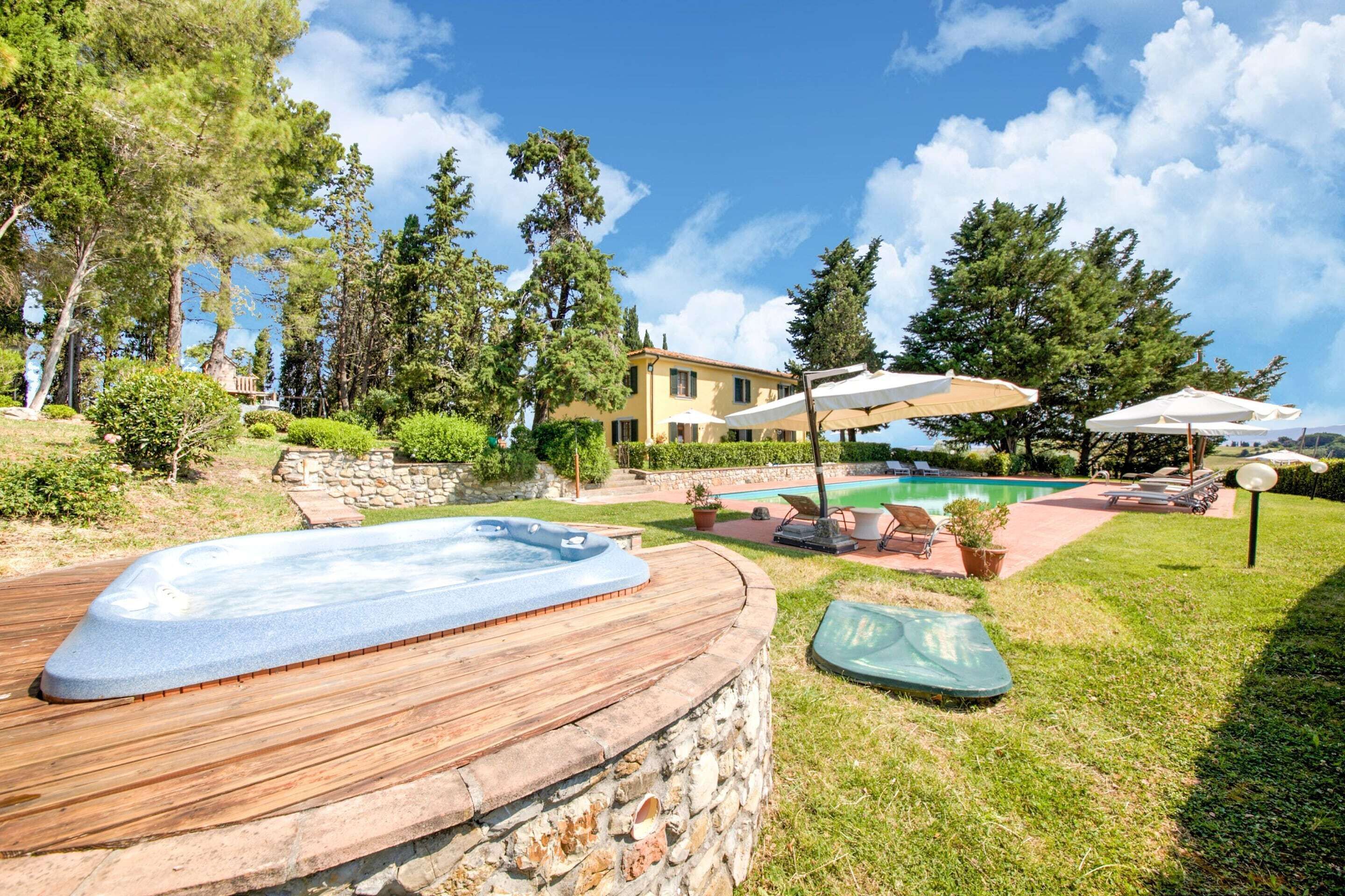 Un área de piscina con jacuzzi, sillas de descanso y sombrillas.