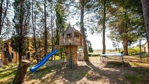 A playground with a slide and a wooden playhouse. - Belvilla by OYO San Francesco Vermentino (Lajatico)