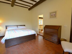 Quarto com cama, cómoda de madeira e uma cadeira.