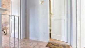 Un pasillo con piso de baldosas, una puerta blanca y una reja de metal.