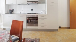A compact kitchen with white cabinets, a stove, and a sink. - Belvilla by OYO Vega (Caprino Veronese)