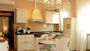 A kitchen with white cabinets, a chandelier, a stove, and a refrigerator. - Villa in Montecarlo With Pool and Scenic Views (Montecarlo)