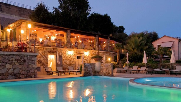 Ein Schwimmbad mit Liegestühlen und ein Restaurant mit Außenbereich.