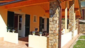 Ein Haus mit Steinaußenseite, Holzbalken und einer gefliesten Terrasse.