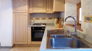 A kitchen with wooden cabinets, a gas stove, a sink, and a marble backsplash. - Holiday Home in Montecarelli With Pool (Barberino di Mugello)