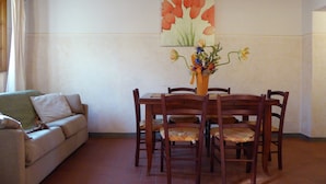 A dining area with a wooden table and chairs, a vase of flowers, and a painting of tulips on the wall. - Holiday Home in Montecarelli With Pool (Barberino di Mugello)