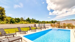 Une piscine avec des chaises longues et une pelouse.