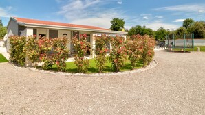 Un bâtiment avec un toit rouge, une véranda et une allée gravillonnée.