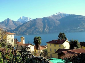 Ein Küstendorf mit traditioneller Architektur, freiem Blick auf den See und Bergen im Hintergrund.