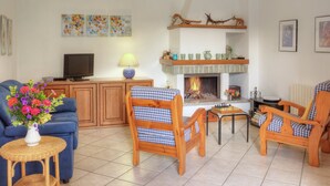 A living room with a fireplace, a television, and a blue sofa. - Sunny & Peacefully Situated House near Center of Village (San Siro)