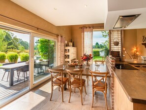 A modern kitchen with a dining area, large windows, and a view of the garden. - Bertrix Charming 2-bedroom Holiday Home (Bertrix)